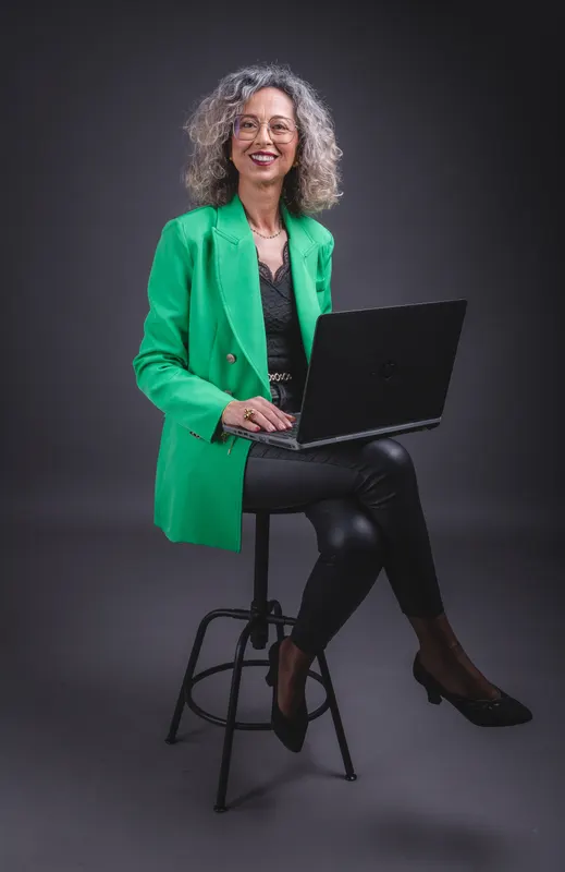 Vanda Pinheiro sentada com o portátil, de casaco verde