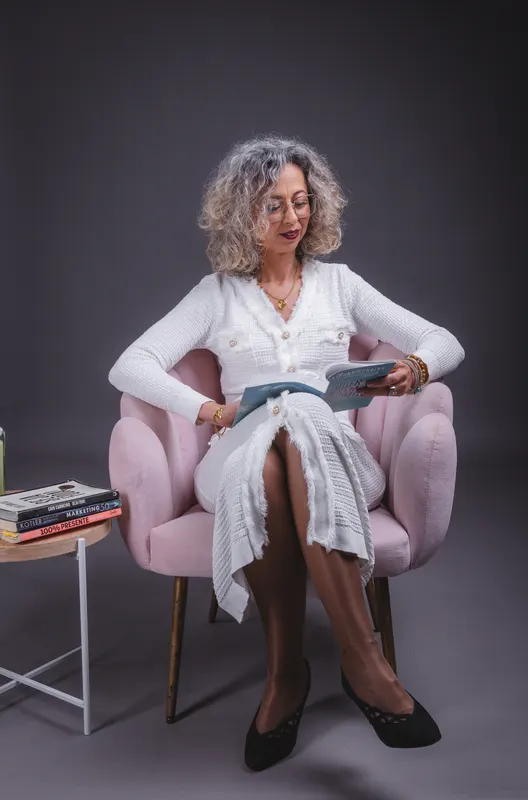 Vanda Pinheiro a ler, sentada num cadeirão rosa